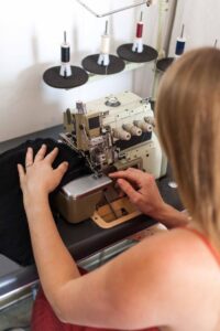 Woman sewing fabric on an industrial sewing machine, focusing on fashion design.