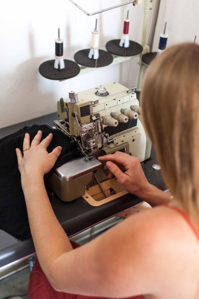 Woman sewing fabric on an industrial sewing machine, focusing on fashion design.